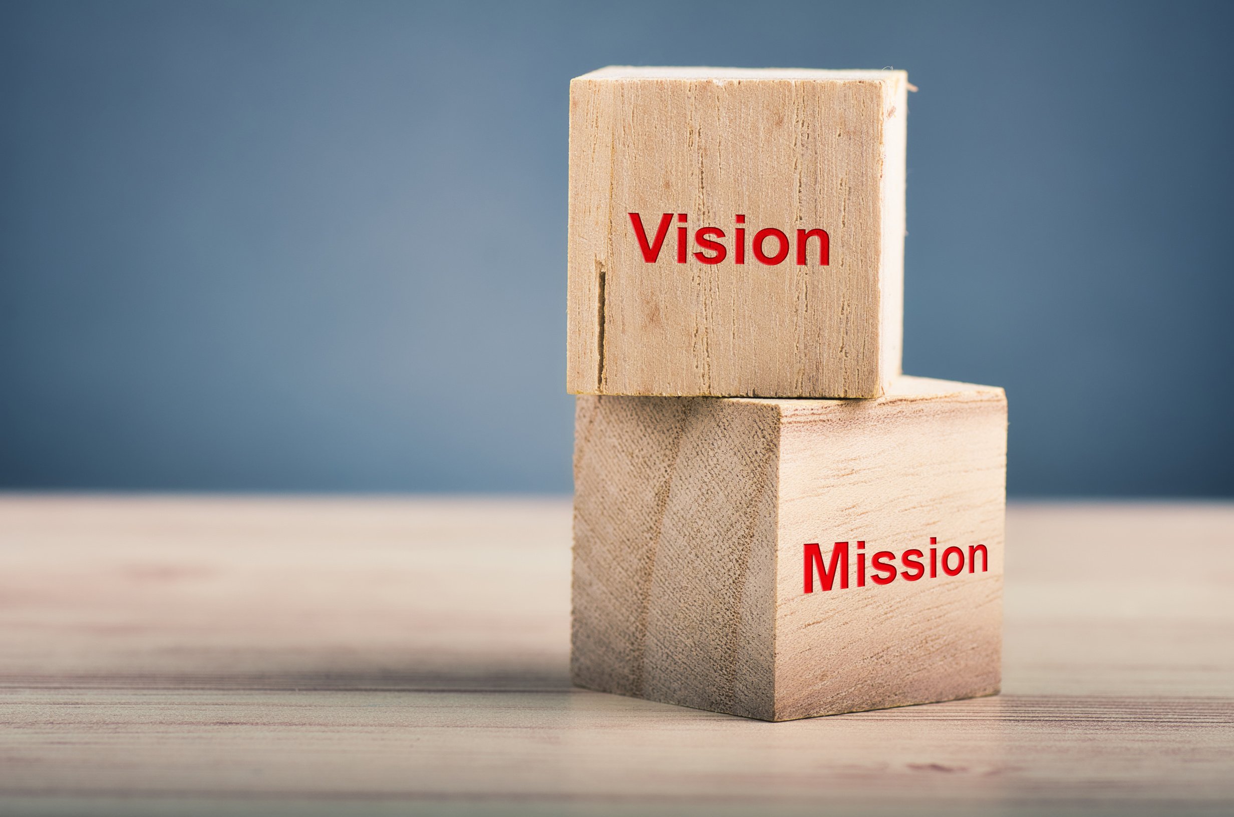 Business success concept, word VISION MISSION on wooden cube over gently lit dark background